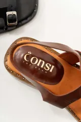 Sandalias negras de cuero con diseño de tiras rectas, hebillas metálicas y un mini taco de 1.5 cm. La suela tiene detalles de tachas pequeñas.