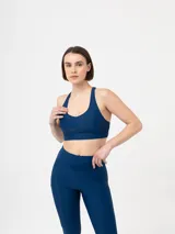 Top deportivo azul marino, tipo bralette o sujetador deportivo, con escote pronunciado y tirantes anchos que se cruzan en la espalda.