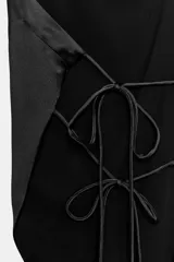 Top satinado negro de cuello halter drapeado con espalda descubierta y bajo asimétrico. Cuenta con cierre en la espalda y cuello con lazada.