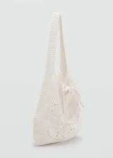 Bolso tipo shopper confeccionado en tejido de crochet de algodón, con diseño de motivos circulares calados, asa de hombro y cierre mediante lazo.