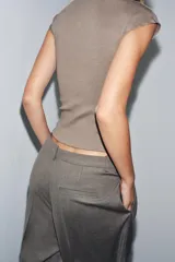 Top negro de tejido de punto, corte ajustado, con cuello alto y mangas sisa caídas.