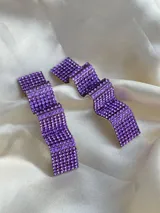 Par de aros colgantes con forma geométrica irregular, cubiertos de strass color violeta.