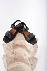 Sandalias negras de cuero con punta cuadrada, tiras capitoneadas y pespuntes blancos a contratono.