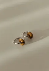 Aros abridores de acero quirúrgico plateado con dije de piedra natural semipreciosa en forma de dona.