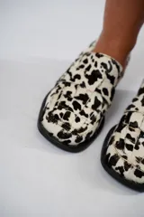 Mocasín de cuero con pelo y estampado de vaca en blanco y negro. Presenta horma cuadrada, diseño enrejillado en la capellada y taco bajo de 4,5 cm.