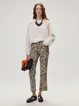 Pantalón de jean de corte recto y tiro medio con estampado floreado multicolor sobre base azul, confeccionado en algodón elastizado.