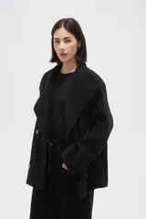 Tapado corto de paño en color beige, con cuello solapa amplio y cierre frontal cruzado con doble botonadura. Presenta mangas largas y bolsillos laterales integrados.