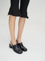 Zuecos clásicos negros de cuero vacuno wax y charol, con taco de madera de 5cm y correa trasera ajustable.