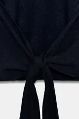 Jersey de punto de cuello subido y manga larga con hombreras. Presenta un diseño de espalda abierta con detalle de nudo.