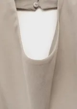 Top color beige, con cuello drapeado, diseño sin mangas, espalda abierta con cierre de lazo y dobladillo asimétrico.
