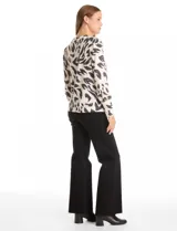 Buzo de hilado fino color blanco con estampado animal print en negro y gris. Cuello redondo, manga larga y detalle de botones dorados en los laterales.