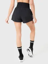 Short deportivo de tiro alto con calza incorporada, pretina ancha elástica y bolsillo interno. Presenta un diseño minimalista en color negro con un pequeño logo bordado en el ruedo.