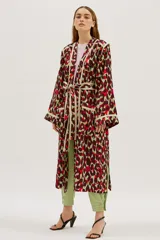 Bata larga estampada con diseño abstracto en tonos borgoña, verde y rojo, con vivos en contraste color crema. Tiene corte recto y amplio, bolsillos delanteros y lazo para ajustar en la cintura.