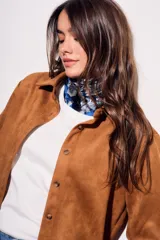 Camisa color marrón de gamuza sintética, de corte recto, con cuello clásico, cierre frontal con botones y mangas largas.