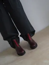 Botas de cuero color marrón con suela track negra y cierre frontal con cremallera roja.