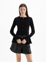 Cardigan negro de tejido de punto semi liviano, con calce al cuerpo, escote redondo y cierre frontal con botones. Mangas largas con puños godet acampanados que aportan volumen.