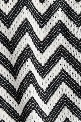 Chaleco corto de punto jacquard con estampado de zigzag en blanco y negro. Presenta escote en V y tiras finas dobles en la parte delantera para anudar.