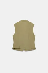 Chaleco entallado color verde militar de cuello subido y manga sisa, con trabillas en los hombros. Cuenta con detalle de hileras horizontales de cordoncillo y botones metálicos dorados en el delantero. Forro interior y cierre frontal con corchetes ocultos.