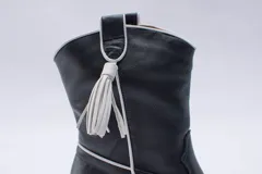 Botas estilo texanas de caña media, confeccionadas en cuero con estampado animal print tipo vaca en blanco y negro. Presentan un diseño de punta fina y taco cuadrado.