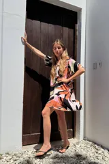 Vestido corto con volados, estampado con formas abstractas en tonos naranja, rosa, negro y verde.