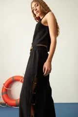 Pantalón marrón de corte recto, con cintura elastizada y cordón ajustable. Presenta mostacillas decorativas en los laterales.