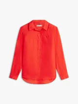 Camisa de corte amplio confeccionada en lino puro, de color rojo, con cuello inglés, mangas largas con puños abotonados, bajo camisero y cierre frontal de botones. Cuenta con el logo de Tommy Hilfiger bordado en el pecho.