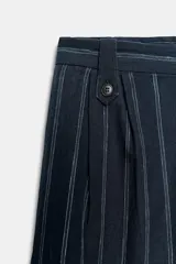 Pantalón de tiro medio confeccionado en mezcla de lino, con diseño de rayas verticales. Presenta cintura con trabillas, bolsillos laterales, pinzas en el delantero y cierre frontal con cremallera y botón.