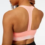 Top deportivo New Balance Pace Bra color salmón con logo en la banda inferior.