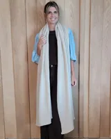 Bufandón de lana 100% lambswool, de diseño largo y versátil, apto para usar como ruana. Presenta una textura suave y liviana en color beige.