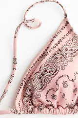 Top de bikini triangular color rosado con estampado paisley en tonos oscuros, con copas con relleno extraíble y tiras para atar en los hombros y en la espalda.
