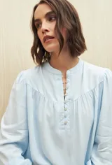 Camisa verde claro de viscosa suave, con cuello mao y botonadura parcial al frente. El detalle de frunces en los hombros y los puños abotonados le suman delicadeza y estilo.