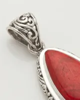 Dije de plata 925 con diseño de filigrana en forma de lágrima, engastado con una piedra natural de coral rojo. Incluye cadena de plata fina.