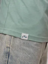 Remera negra de algodón con estampado en la espalda con palmeras, tabla de surf y texto en color blanco y fucsia.