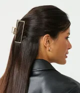 Pinza de pelo rectangular dorada con dientes espaciados y agarre redondo.