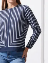 Blusa de gasa estampada con líneas verticales negras sobre fondo beige, de manga larga con puño abotonado. Espalda con abertura y botón.