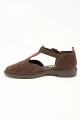Sandalias cerradas de cuero marrón, con diseño tipo Mary Jane con tira en T, detalles perforados en la puntera y suela plana con pequeño tacón.