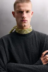 Sudadera de ajuste regular, color verde oliva, con cuello redondo y manga larga. Presenta una textura irregular en el tejido, similar al borreguito o bouclé.