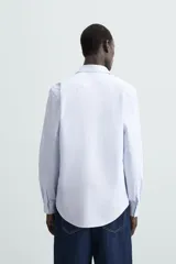 Camisa de algodón de manga larga, color celeste claro, con cuello italiano y cierre frontal de botonadura.