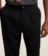 Pantalón de sastrería negro de corte recto, con trabillas, elástico trasero en la cintura, bolsillos laterales y cierre tradicional.