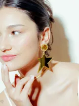 Caravanas doradas con base circular de strass y perlas, y un colgante en forma de estrella de acrílico espejado.