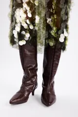 Bota de caña alta confeccionada en cuero vacuno con textura de reptil. Presenta un diseño de punta fina y un tacón bajo tipo kitten heel.