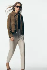 Pantalón de tiro alto color beige, con detalle de costuras marcadas en el delantero y la espalda. Incluye bolsillos delanteros de vivo y cierre frontal con cremallera, botón interior y gancho metálico.