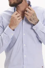 Camisa de manga larga con diseño de rayas verticales finas en color celeste y blanco, con cuello clásico y cierre frontal de botones.