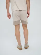 Bermuda Umbro de hombre, color beige, confeccionada en tejido de algodón con bolsillos laterales y cintura elástica con cordón de ajuste.