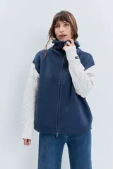 Cardigan de punto con diseño bicolor, cuerpo en color marrón y mangas largas en color crema con textura trenzada. Presenta cuello polo, cierre frontal con cremallera y puños acanalados.