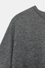Remera oversize gris melange de tejido fluido, con cuello redondo y mangas cortas amplias.