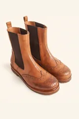 Bota tipo Chelsea de cuero vacuno color suela, con diseño brogue en la puntera y laterales. Presenta paneles elásticos laterales en color marrón oscuro, tirador trasero y suela de goma con plataforma.