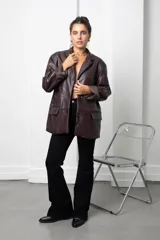 Blazer de eco cuero color bordó, con diseño oversize, hombreras estructuradas y solapas clásicas. Presenta mangas largas con puños vueltos y cierre frontal con botón.