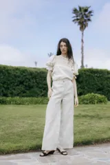 Pantalón de lino de pierna amplia y corte recto, color beige, con trabillas para cinto y cierre frontal con botón.