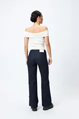 Jean negro de calce flare con cinturón incorporado en la misma tela y silueta ajustada en cadera que se ensancha hacia el ruedo.